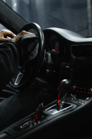 pexels-photo-6872585-6872585 Close-up of a person cleaning a car's dashboard and steering wheel, focused on interior maintenance.